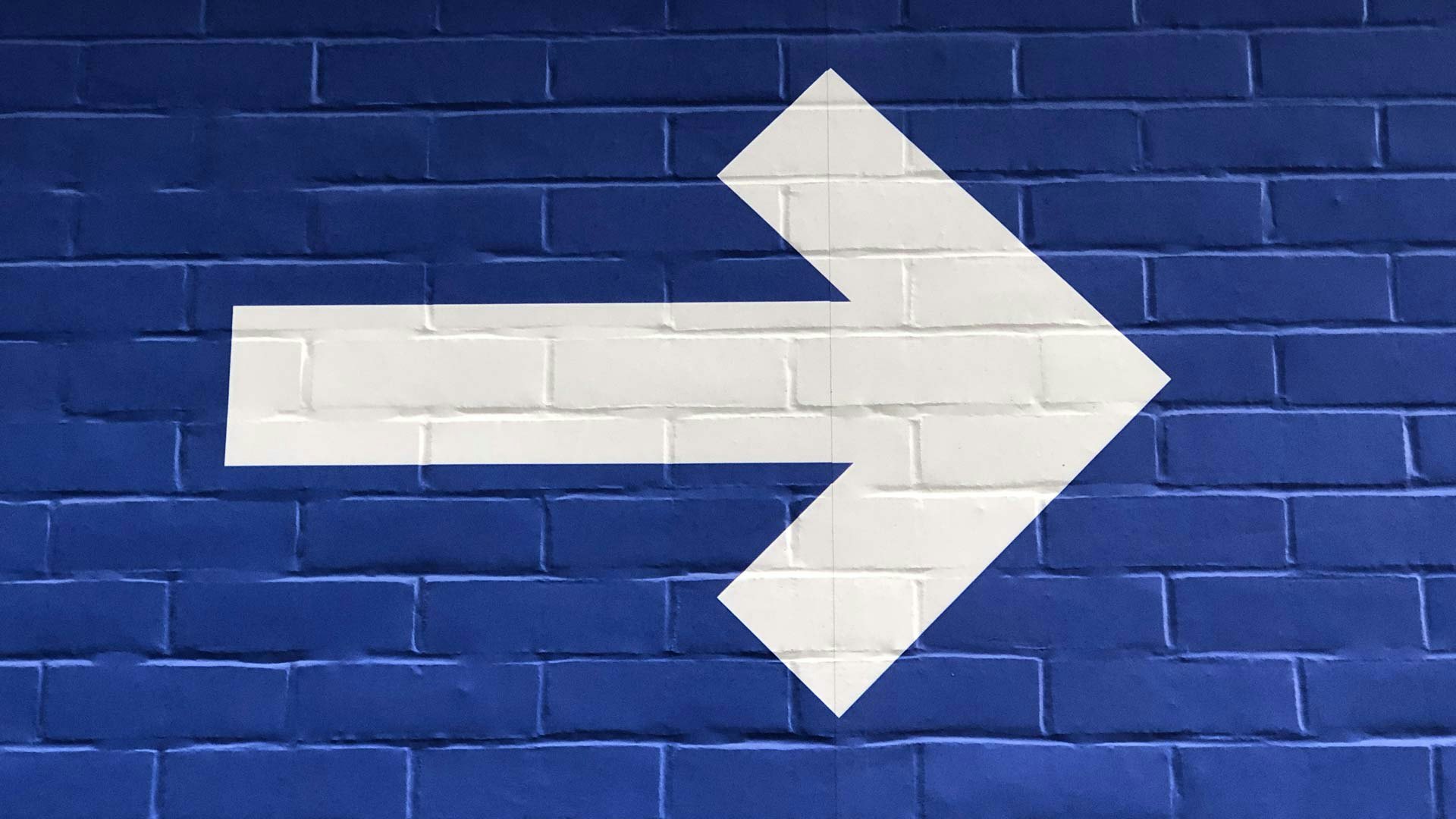 White Arrow on Blue Brick Wall